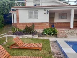 une maison avec un banc à côté d'une piscine dans l'établissement La Chuña, à Villa Los Aromos