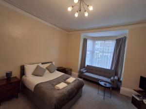 a bedroom with a bed and a couch and a window at Inn By The Sea, Portsmouth - EN SUITE Rooms with Sea View Possible, parking EV 22kW in Portsmouth