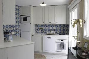a kitchen with white cabinets and blue tiles at Playa Salinas Grupo Terra De Mar in Calpe