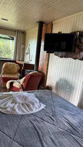Un dormitorio con una cama y un televisor de pantalla plana. en Chalé 10 com hidromassagem Kayser Haus, en Urubici