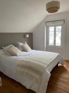 a white bed in a bedroom with a window at La villa Alixel in Pléneuf-Val-André