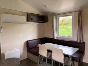 a dining room with a table and chairs and a window at Le Camping de Ripan in Bessenay