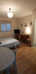 a bedroom with a bed and a table and a television at la chambre de Valérie in Saint-Bonnet-de-Mure