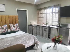 a bedroom with a bed and a kitchen and a table at Peaceful Stay - Suite 5 in Sasolburg