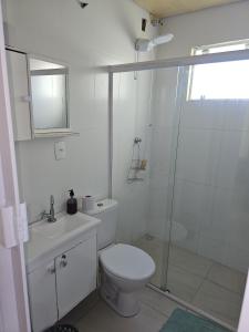 a white bathroom with a toilet and a shower at Estúdio Central 76 in Ponta Grossa +10 photos