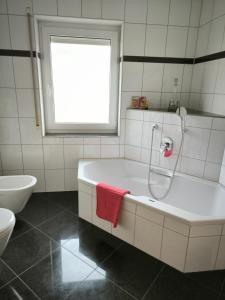 a white bathroom with a tub and a sink at Weinbergblick in Kirchheim am Neckar +15 photos