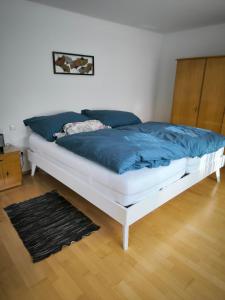 a white bed with a blue blanket on it in a room at Weinbergblick in Kirchheim am Neckar