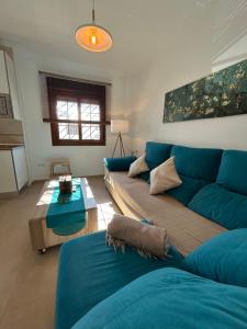 a living room with a blue couch and a table at Apto con vistas Virgen del Carmen in El Rompido