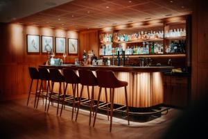 a bar with four stools in front of it at Hotel Austria Lech in Lech am Arlberg