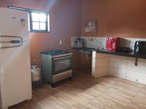 a small kitchen with a stove and a refrigerator at Chacara vila geovana suites in Pirenópolis