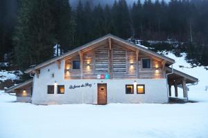 a log cabin in the snow with lights on it at La Ferme du Praz in Les Contamines-Montjoie