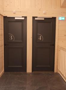 two black doors in a building with numbers on them at La Ferme du Praz in Les Contamines-Montjoie