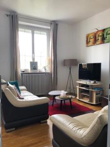 a living room with a couch and a tv at Les Hauts du Tertre Notre Dame in Saint-Brieuc