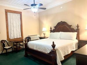 a bedroom with a bed and a ceiling fan at The Eastland Historic Hotel- Imperial Room in Eastland +9 photos