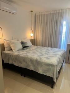 a bedroom with a bed with white sheets and a window at Lindo apartamento próximo do mar novinho in Bombinhas +83 photos