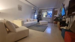 a living room with a white couch and a tv at Ghamarth Mikonos in Gammarth