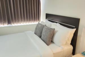 a white bed with pillows sitting next to a window at 1 - Serenity Suite - 1 - Reese Tower in Tulsa