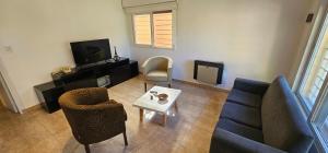 a living room with a couch and chairs and a tv at Casa familiar con doble patio, cochera, fácil acceso en el centro de Escobar in Belén de Escobar