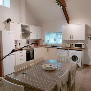 a kitchen with a table and chairs and a kitchen with white cabinets at The Milking Parlour in Llandeilo