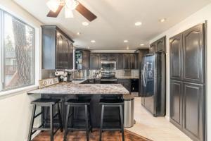 a kitchen with black cabinets and a large island with bar stools at The Affordable Family Fun House- Ping Pong, Pool Table, Darts in Post Falls