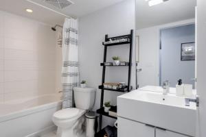 a white bathroom with a toilet and a sink at Exquisitely Furnished 1BR Suite in DWTN Toronto in Toronto +22 photos