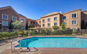 a swimming pool in a courtyard with apartment buildings at Ayres Hotel Chino Hills Ontario in Chino Hills