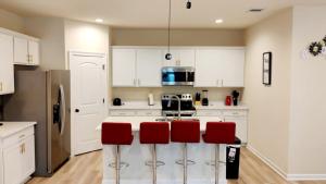a kitchen with white cabinets and red bar stools at Geaux to Mike The Tiger Retreat Near LSU - CB1021 in Baton Rouge