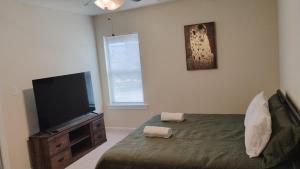 a bedroom with a bed and a flat screen tv at Geaux to Mike The Tiger Retreat Near LSU - CB1021 in Baton Rouge
