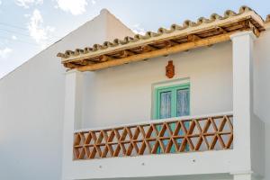 a white house with a green window and a balcony at Casa de la Tita Belén in La Puebla de los Infantes