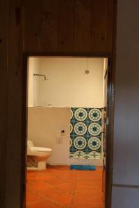a bathroom with a toilet and a tile wall at Los Cruxes in Tepoztlán