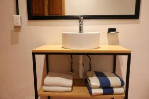 a bathroom with a sink and towels on a shelf at Los Cruxes in Tepoztlán