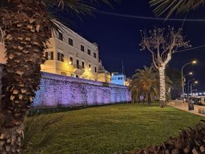 un edificio con una pared y palmeras por la noche en HOME N & C Noemi & Costa, en Bari