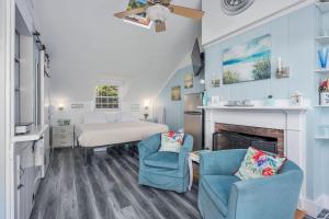 a bedroom with a bed and two chairs and a fireplace at Seaside Cottages - Cottage 32A - Seaside Too in South Yarmouth