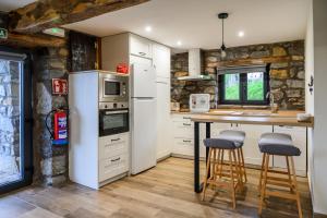 a kitchen with white appliances and a counter with stools at La cabañuca apartamento La Garma in Quintana