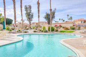 a swimming pool with palm trees in a resort at Steps to Indian Wells Condo with Golf Course Views! in La Quinta
