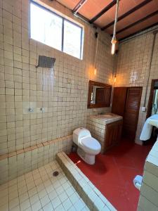 a tiled bathroom with a toilet and a sink at Los Cruxes in Tepoztlán