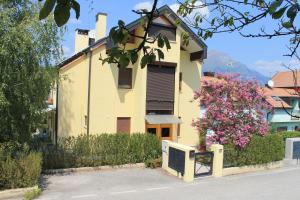 a yellow house with a fence and a pink flower at De Bati in Belluno