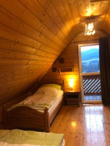 a bed in a wooden room with a window at Beskidzka Chatka in Wysowa-Zdrój