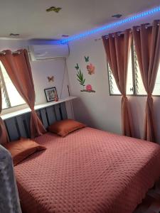 een slaapkamer met een bed met oranje lakens en ramen bij Charmant appart in Fort-de-France +29 foto's