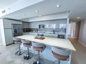 una cocina con encimera blanca y taburetes de bar en Luxury 3 bedroom condo with pool, en Hallandale Beach