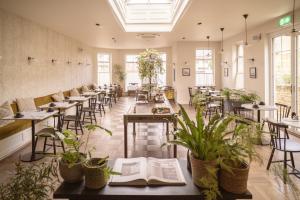 ein Restaurant mit Tischen, Stühlen und Pflanzen in der Unterkunft Leighton House - Boutique Guesthouse in Bath