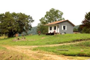 a small white house on a grassy hill at Chalé dos Sonhos e Encantos em Monjolinho in Ponte Alta