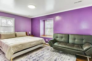 a purple bedroom with a bed and a leather couch at 6 Mi to Spectrum Center: Spacious Getaway w/ Deck in Charlotte