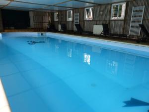 a large swimming pool with blue water at Country home with indoor pool 20 pers in Cléguérec