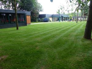 a large grassy yard with a building in the background at Country home with indoor pool 20 pers in Cléguérec