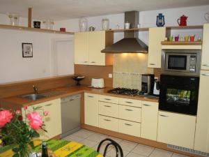 a kitchen with white cabinets and a stove top oven at Country home with indoor pool 20 pers in Cléguérec