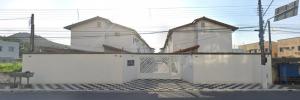 two white buildings with a gate in a street at Casa Tomazella in Guarujá