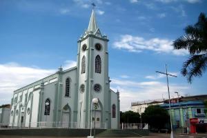 a white church with a steeple with a clock tower at Hotel Coutinho in Pirapora