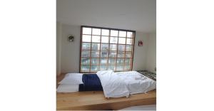 名古屋市にあるNagoya Hostel The Three Smiles / Vacation STAY 13462の大きな窓のある部屋のベッド