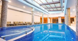 a large swimming pool with chairs in a building at Predela 2 Aparthotel in Bansko